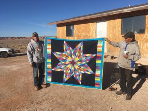 Two Dineh Men displaying original art hand crafted woven rug